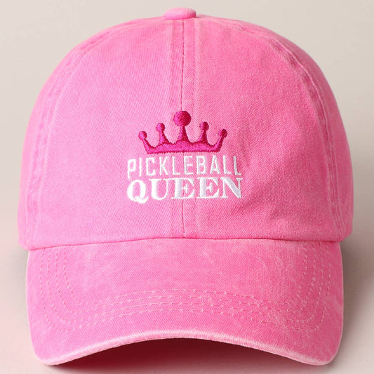 A pink baseball cap with 'PICKLEBALL QUEEN' embroidered on the front in white, accompanied by a small crown motif.