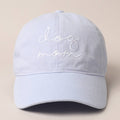 A light blue baseball cap with 'Dog Mom' text embroidered on the front.